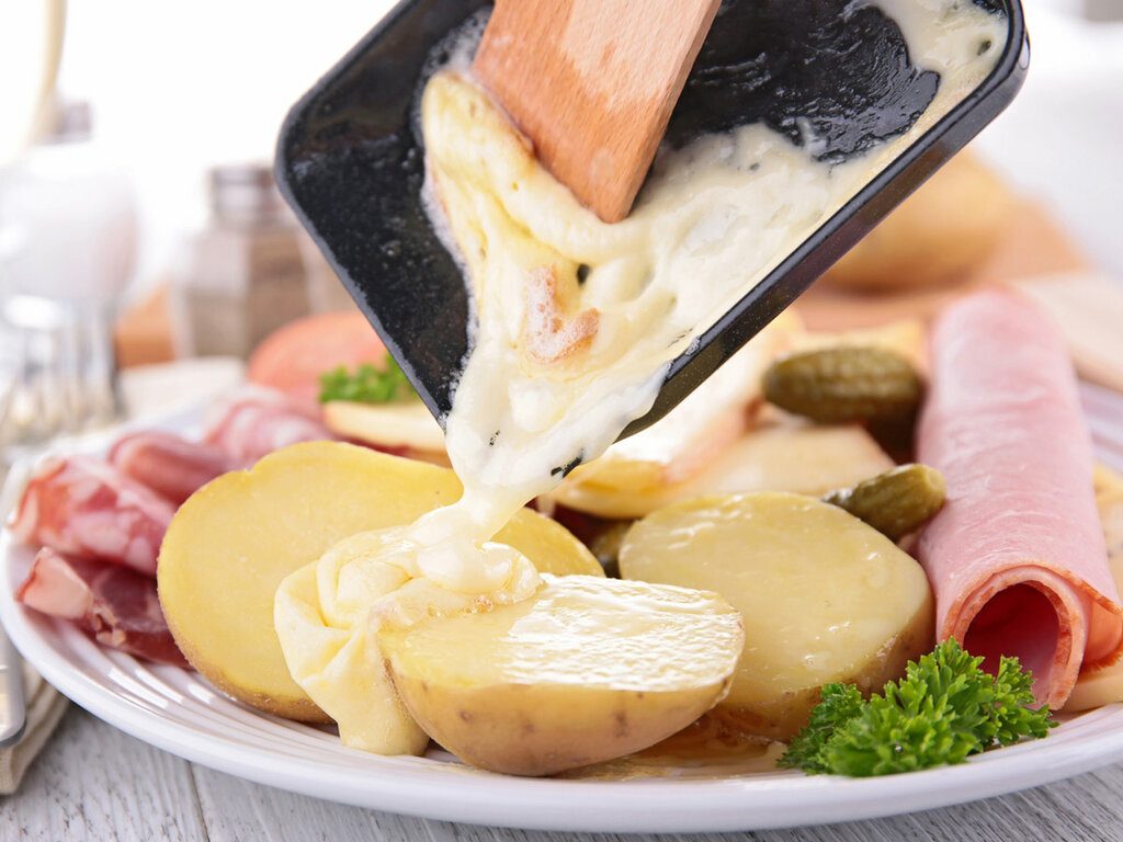 Melted raclette cheese served with potatoes and accompaniments